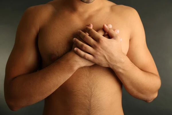 Young man with chest pain on grey background