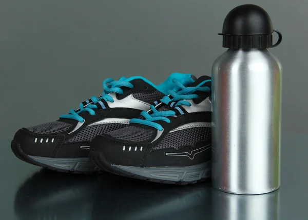 Sports bottle and sneakers on grey background