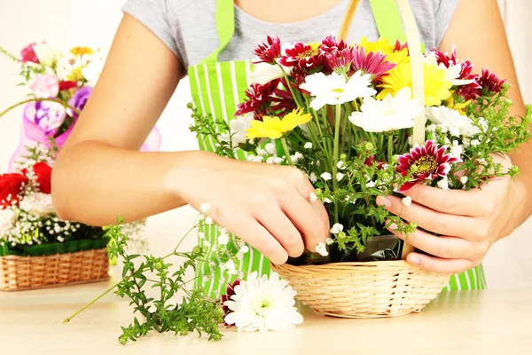 Florist makes flowers bouquet in wicker basket