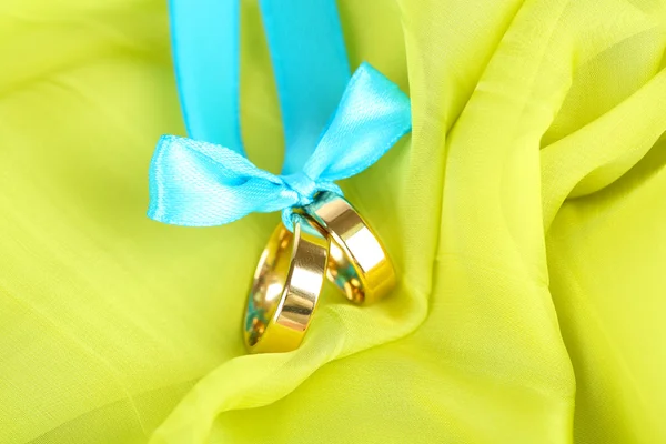 Wedding rings tied with ribbon on bright fabric