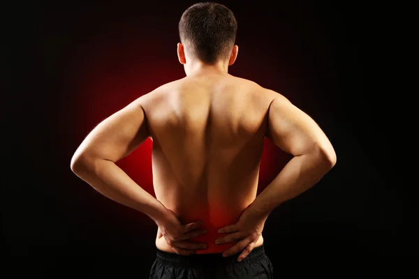 Young man with back pain, on red background — Stock Photo #32778333