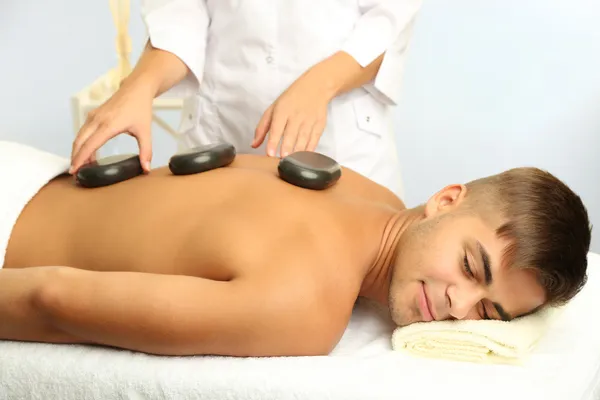 Young man having stone massage in spa salon