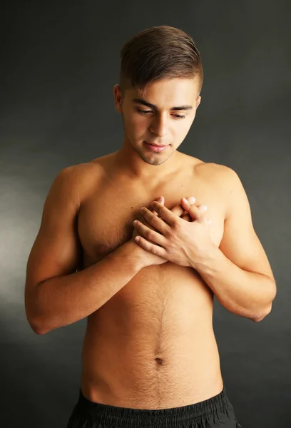 Young man with chest pain on grey background