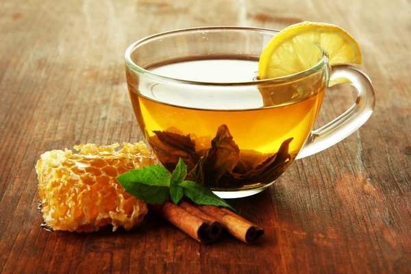 Transparent cup of green tea with honey and cinnamon on wooden background