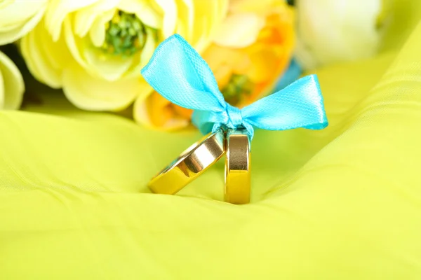Wedding rings tied with ribbon on bright fabric
