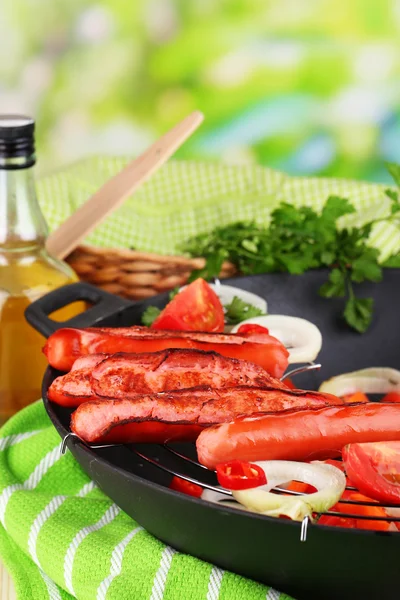 Delicious sausages with vegetables in wok on wooden table on natural background
