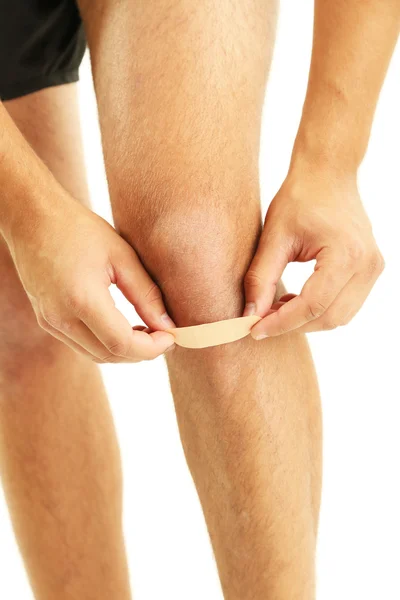 Young man with adhesive bandage on knee, isolated on white