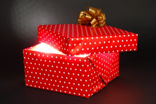 Gift box with bright light on it on dark grey background