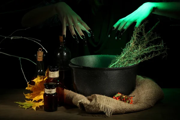 Witch in scary Halloween laboratory on dark color background