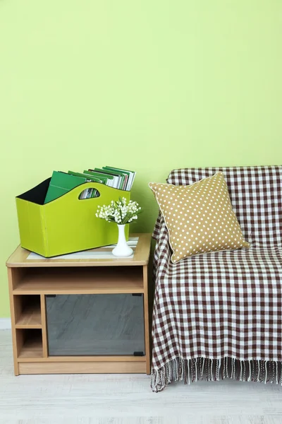 Magazines and folders in green box on bedside table in room