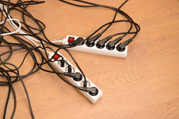 Overloaded power boards, on wooden floor background