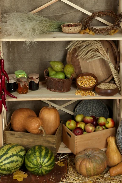 Fruits and vegetables with jars of jam and bowls of grains on shelves close up