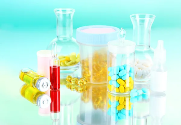 Medical bottles and pills on green background