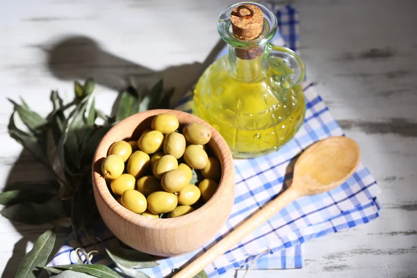 Olive oil and olives in bowl on on napkin wooden table
