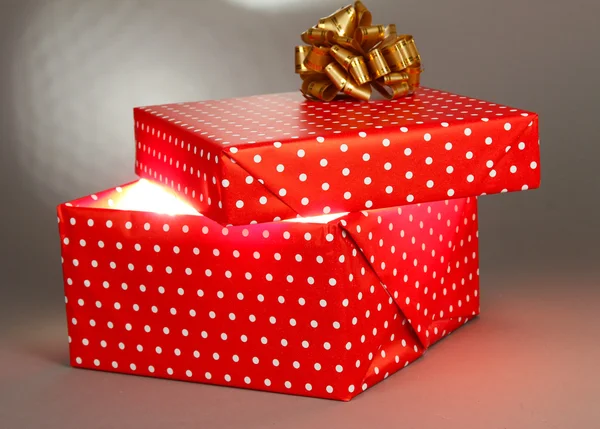 Gift box with bright light on it on grey background