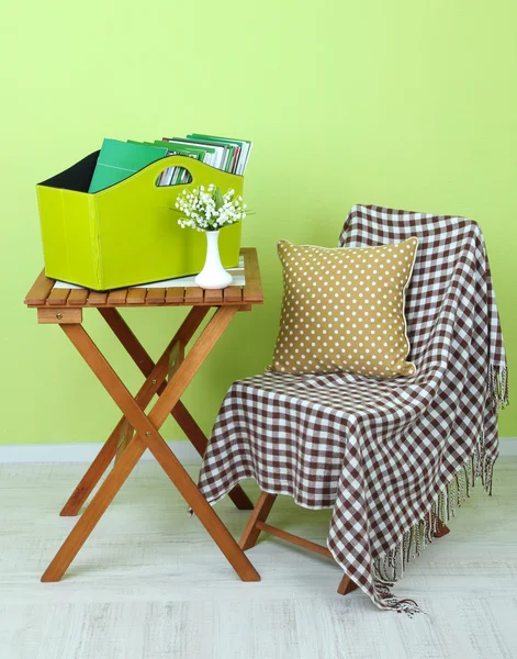 Magazines and folders in green box on table in room