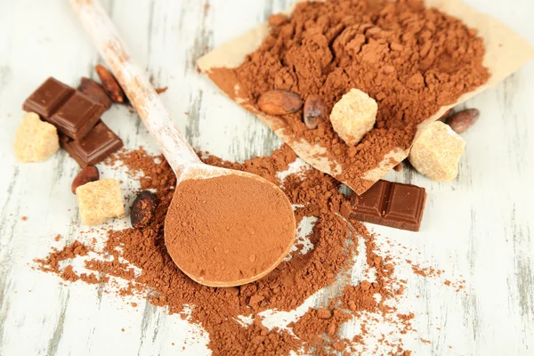 Cocoa powder in spoon on wooden table