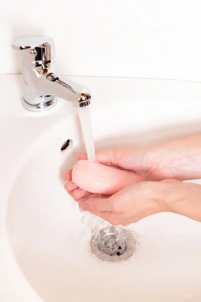 Close-up of human hands being washed under faucet in bathroom