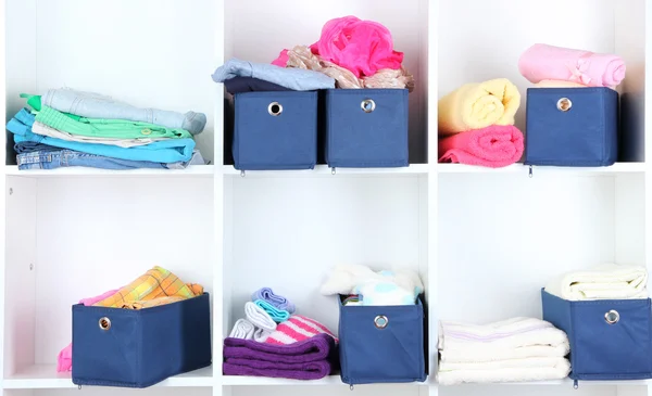 Blue textile boxes with towels and clothes in white shelves