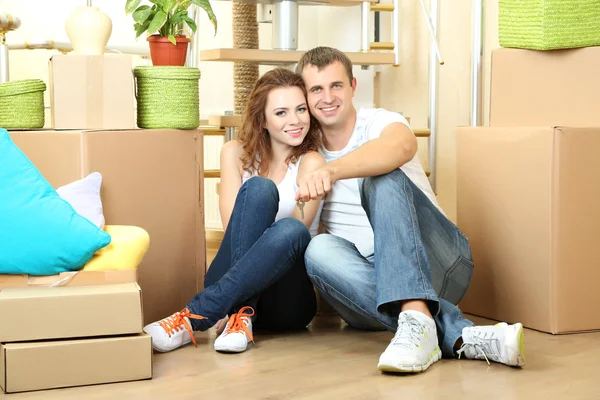 Young couple sitting in new house on staircase background