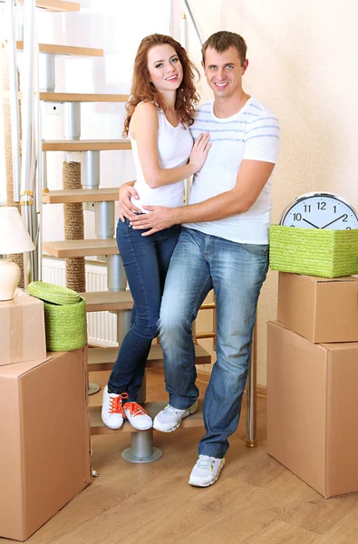 Young couple with boxes in new home on staircase background