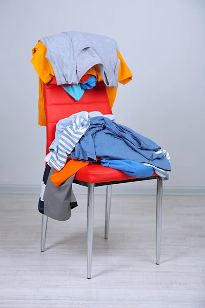 Heap of clothes on color chair, on gray background
