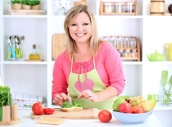 Happy smiling woman in kitchen preparing sandwich