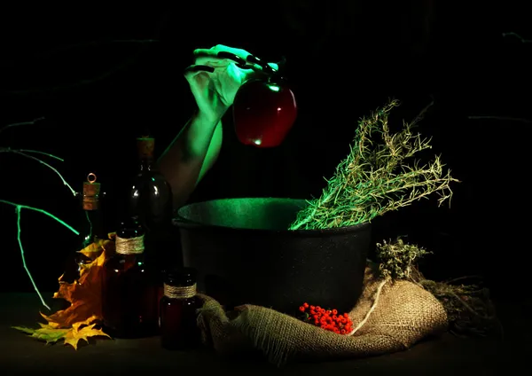 Witch in scary Halloween laboratory on dark color background