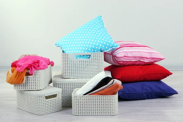 Plastic baskets with things in floor on room background