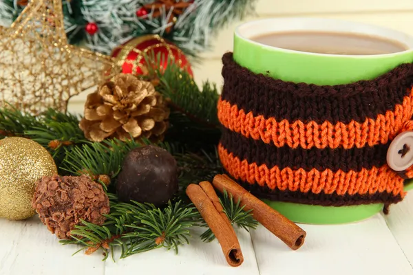 Cup of hot cacao with chocolates and Christmas decorations on table on wooden background