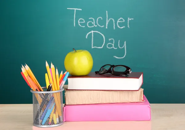 School supplies on blackboard background with inscription Teacher Day