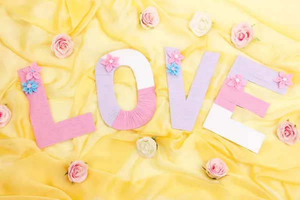 Word Love created with brightly colored knitting yard on fabric background