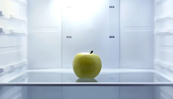 One apple in open empty refrigerator. Weight loss diet concept.