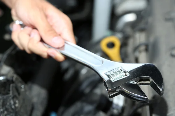 Hand with wrench. Auto mechanic in car repair