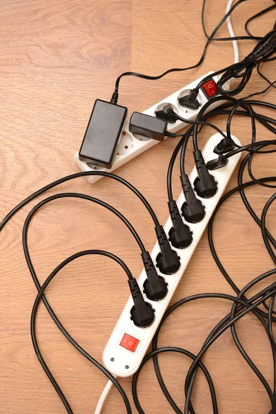 Overloaded power boards, on wooden floor background