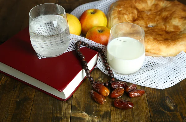 Composition with traditional Ramadan food, holy book and rosary, on wooden background