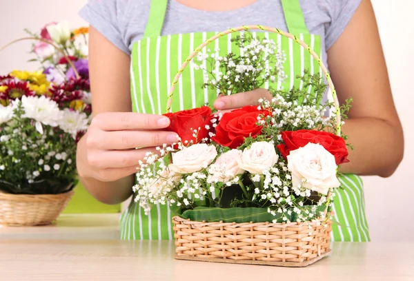 Florist makes flowers bouquet in wicker basket