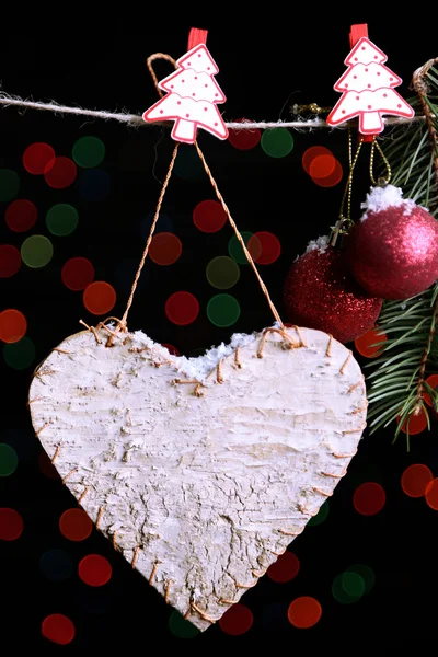 Blank heart and Christmas accessories on black background with lights