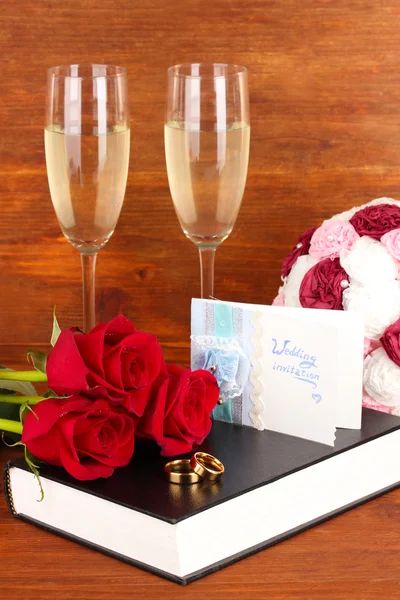 Wedding rings on bible with roses and glasses of champagne on wooden background