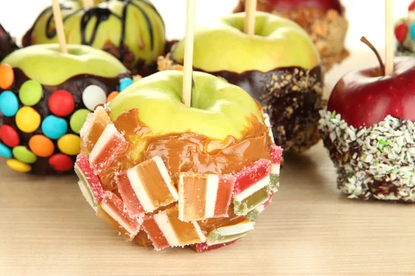 Candied apples on sticks on wooden table close up