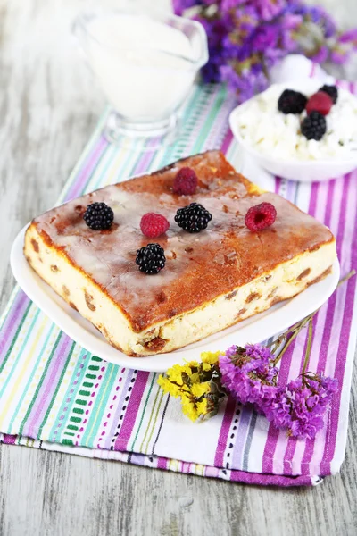 Cheese casserole with raisins on plate on napkin on wooden table close-up