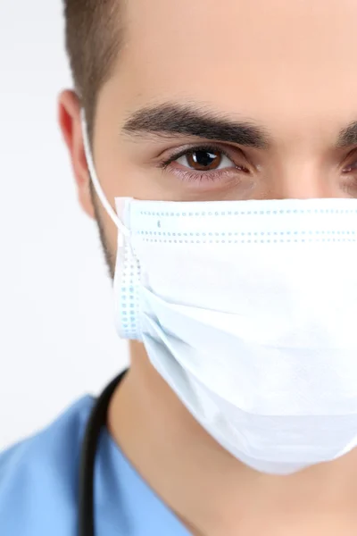 Young male doctor in medical mask, close-up, isolated on white