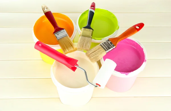 Set for painting: paint pots, brushes, paint-roller on white wooden table