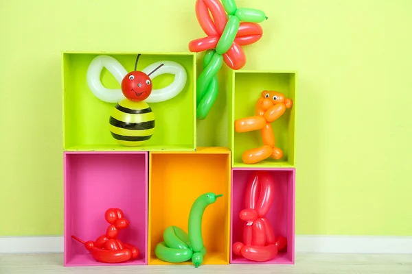 Simple balloon animals and other toys on shelves, on bright background