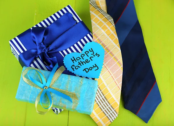 Happy Fathers Day tag with gift boxes and tie, on wooden background