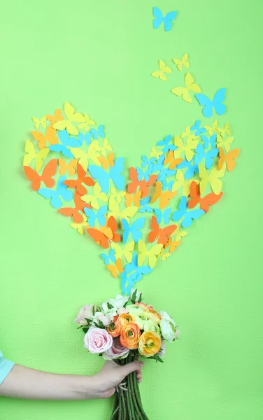 Paper butterflies fly out of flowers on green wall background