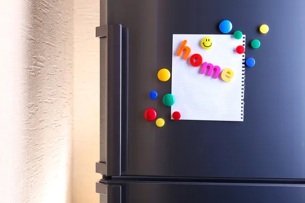 Empty paper sheets and colorful magnets on fridge door