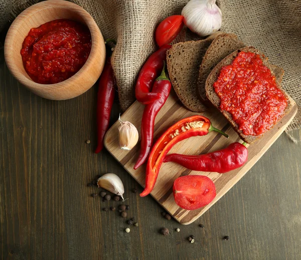 Composition with salsa sauce,, red hot chili peppers and garlic, on sackcloth, on wooden background