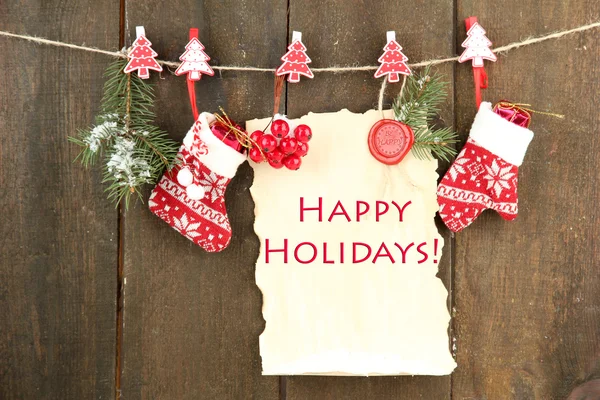 Blank sheet with Christmas decor hanging on grey wooden wall