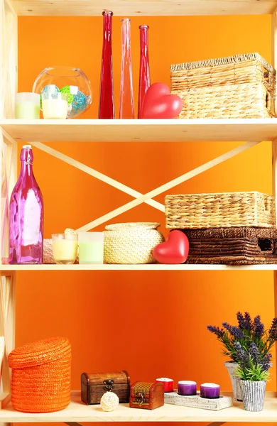 Beautiful white shelves with different home related objects, on color wall background